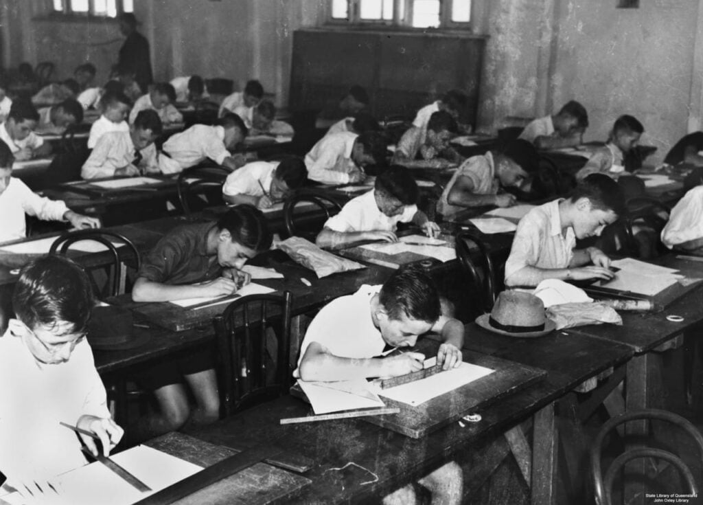 Vintage black-and-white photo of schoolboys taking an exam in a classroom